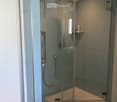 Modern bathroom with a glass-enclosed shower stall featuring a handheld showerhead and a built-in shelf. The shower stall has a sleek, contemporary design with a glass enclosure and a tiled interior.