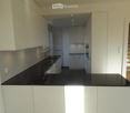 Modern kitchen with white cabinets, black countertop, built-in oven, and sink. The space is well-lit with recessed lighting and features a sleek, contemporary design.