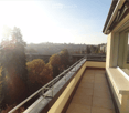 Balcony with tiled floor, metal railing, and scenic city view with trees and buildings.