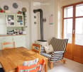 A cozy living and dining area with a wooden dining table, chairs, a striped sofa, a cabinet, and a fireplace.
