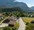 A scenic view of a village nestled in a valley with houses, a road, and surrounding mountains.
