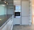 Modern kitchen with white cabinets, stainless steel appliances, and a dark countertop.