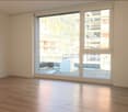 Empty room with wooden flooring, large windows, and white walls. No furniture or equipment present.