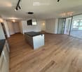 Empty room with wooden flooring, white walls, and large glass sliding doors leading to a balcony area.