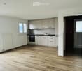 Modern kitchen with light-colored cabinets, stainless steel appliances, and wooden flooring.
