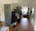 Bright hallway with wooden flooring, coat rack, and a cat tree visible in the background.