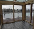 Empty room with large glass doors leading to a balcony or terrace, wooden flooring, and a view of the surrounding area.