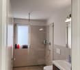 modern bathroom, shower enclosure, glass door, white tiles, modern fixtures, vanity, sink, toilet, window, rugs