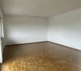 Empty room with white walls and hardwood flooring.