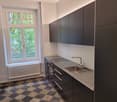 black checkered flooring, stainless steel countertops, large sink, oven, large window, radiator