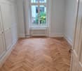 Empty room, wooden parquet floor, white walls, white doors, window with white radiator, parquet floor