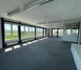 large room, fluorescent lighting, grey carpet, large windows, exterior views