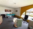 empty room with a massage table, a chair, a desk, a cabinet, a trash bin, and a window with a view of the outside