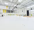 Large open-plan commercial space with high ceilings, exposed beams, and ample natural light from the windows. The space appears to be a studio or event venue with a stage-like platform and lighting equipment installed.