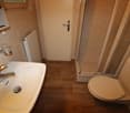 Bathroom with wooden floor, sink, toilet, shower, and heating