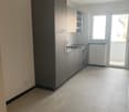 modern kitchen with tiled floor, gray cabinets, central island with sink, gas stove, oven