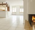 white tiles, fireplace, open area, two windows, kitchen bar
