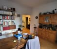 room with wooden table, wooden chairs, desk, shelves with books, wooden cabinet, stool, wooden sideboard, and chair
