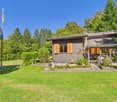Detached house, wood exterior, orange shutters, covered terrace, flagpole, garden, lawn, trees