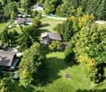 Multiple small houses in a rural area with green grass and trees.