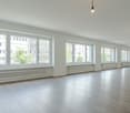 large room, hardwood floors, large windows, white walls, white radiators, ceiling lamps