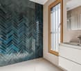 blue tiled herringbone shower, glass door, sink, mirror, white cabinets