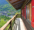 wooden balcony, wooden railing, red shutters, concrete floor, view of mountains and village
