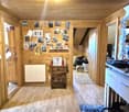 Cozy wooden cabin interior with a wall covered in photos and artwork, a wooden cabinet, and a blue cabinet. The room has a wooden ceiling and floor.