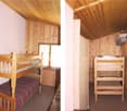Rustic wooden cabin interior with bunk beds, wooden walls and ceiling, and striped bedding
