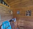 Wooden cabin interior with shelves, framed photos, and a cabinet with various items