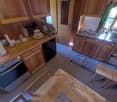 Wooden cabinets, countertop, stove, dishwasher, various kitchen appliances and utensils