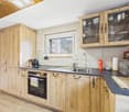 kitchen with wooden cabinets, black countertops, sink, oven, stove, windows, natural light