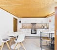 modern kitchen with white cabinets, wooden ceiling, white dining table, white chairs, oven, sink, countertop, basket, clock