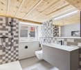 modern bathroom with wooden ceiling, checkered tiles, white sink, toilet, shower, mirror