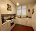 White cabinets, tiled backsplash, gas stove, oven, kitchen sink, refrigerator