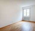 empty room with hardwood floors, white walls, window, and white radiator