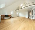 Empty room with wooden floor, white walls, fireplace, spiral staircase, windows, radiators