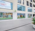 Commercial building with several glass windows, plants, and a large sign indicating parking space availability