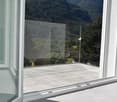 Large windows with a view of the mountainous landscape outside, concrete floor, white walls