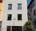 3 story house, white exterior, metal railings, 3 balconies, 1 garage, stone walkway