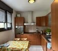 kitchen, wooden cabinets, white tiles, gas stove, sink, refrigerator, dishwasher, oven, blender, window, curtains, dining table, chairs