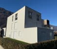 Modern design house, white exterior, glass railing on terrace, multiple windows, garage entrance