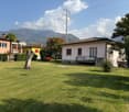 House located in front of a lawn with mountains in the background.