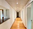 Empty hallway with wooden floor, white walls, glass doors, and a marble countertop.