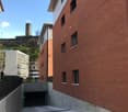 Red brick building, multiple windows, concrete parking area, metal fence, underground garage