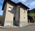 2 story house, beige exterior, black roof, windows with white shutters, small garden, paved driveway