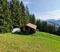 wooden cabin on a hillside, solar panel on the neighboring cabin