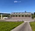 Large building with multiple windows, large parking lot, wide driveway