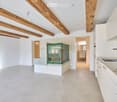Empty room with tiled floor, exposed wooden beams, white walls, and modern kitchen area with a sink and cabinet