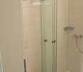Bathroom with toilet, glass shower door, and white tiles